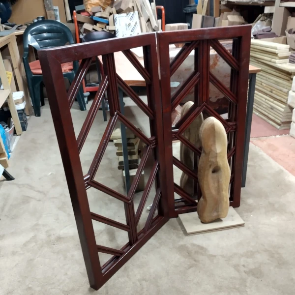 Wooden pagoda panels in workshop, one with mirror behind and human figure like carving in front.